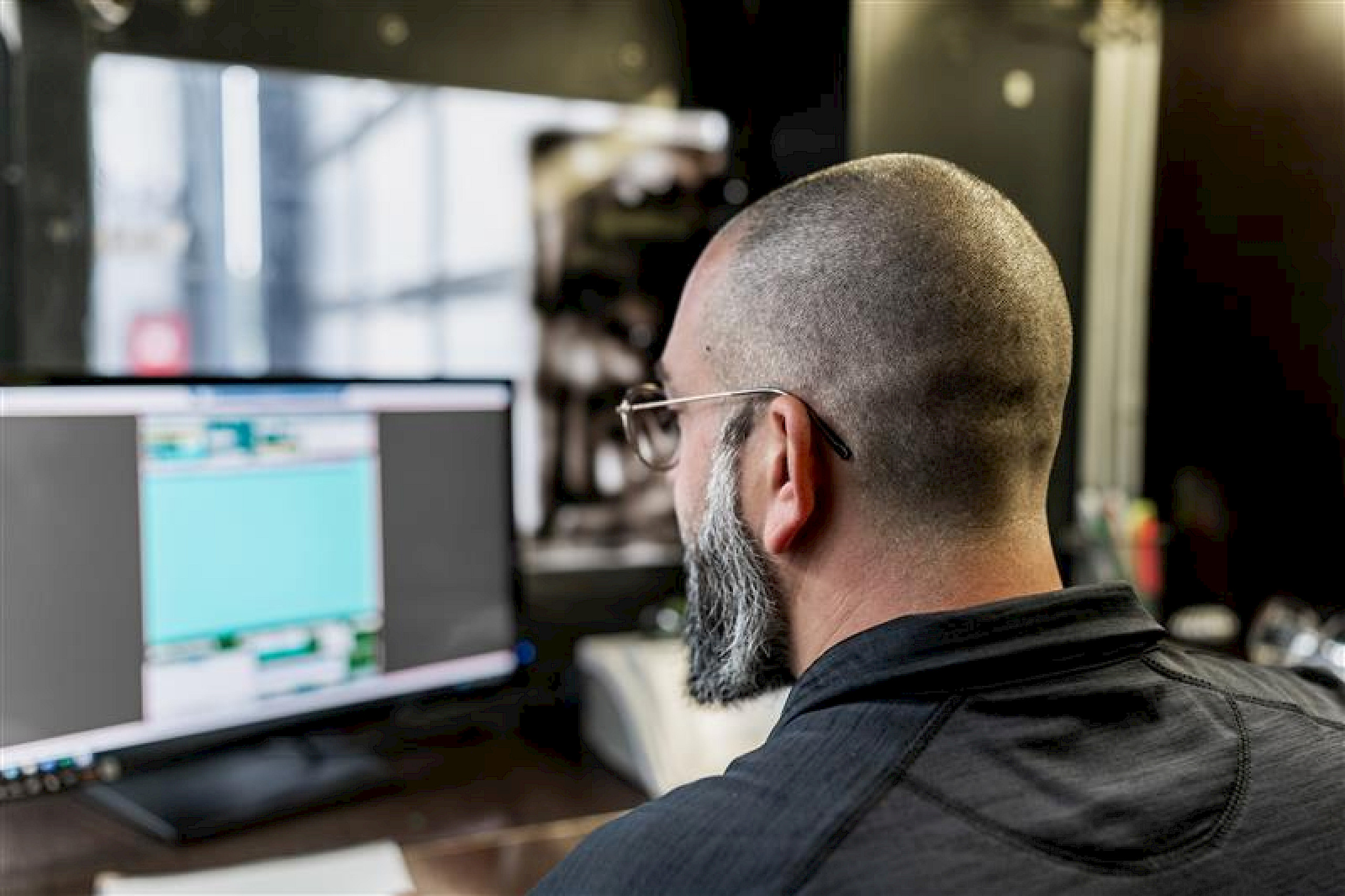 Ein Mann mit Brille und Glatze sitzt vor einem Computerbildschirm.