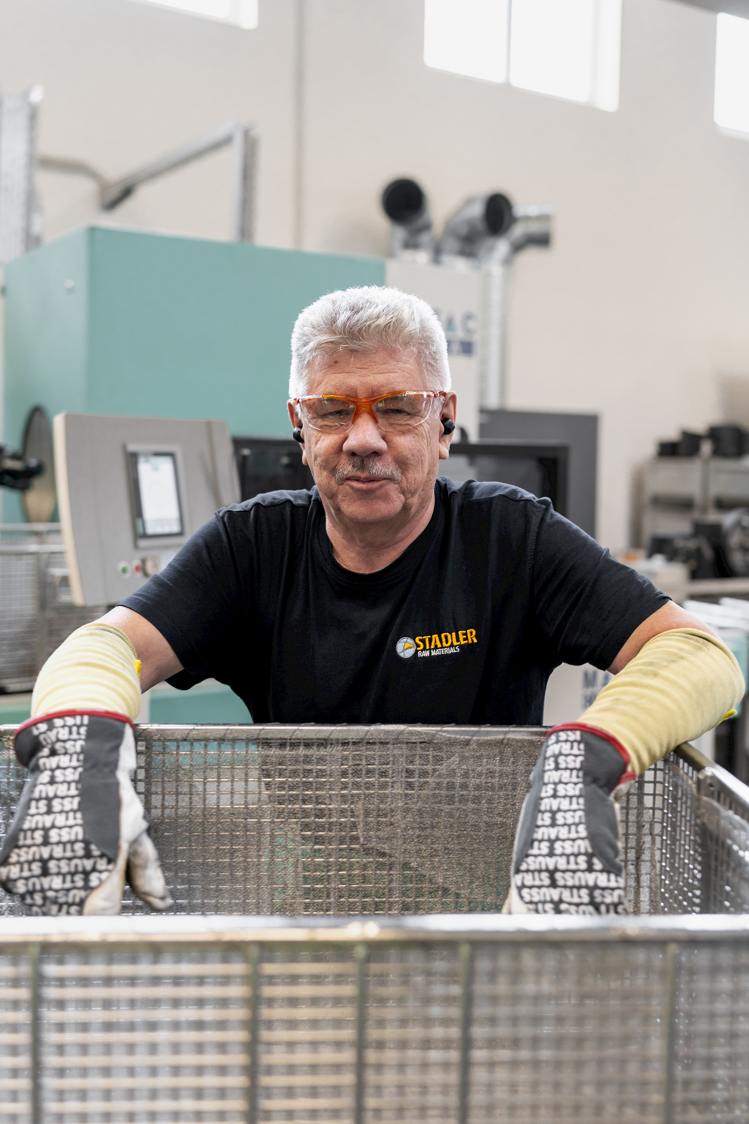 Ein Mann mit Schutzbrille und T-Shirt mit Stadler-Logo lächelt in die Kamera.