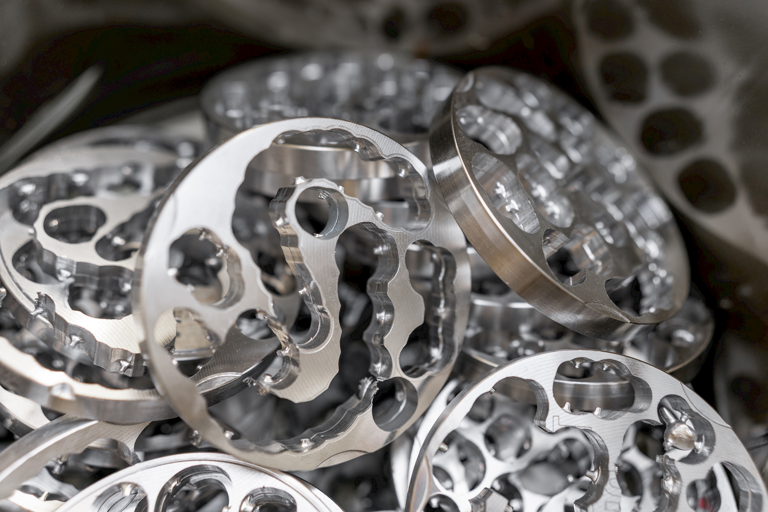 Silberne, runde Metallteile mit mehrfachen Aussparungen, gestapelt.